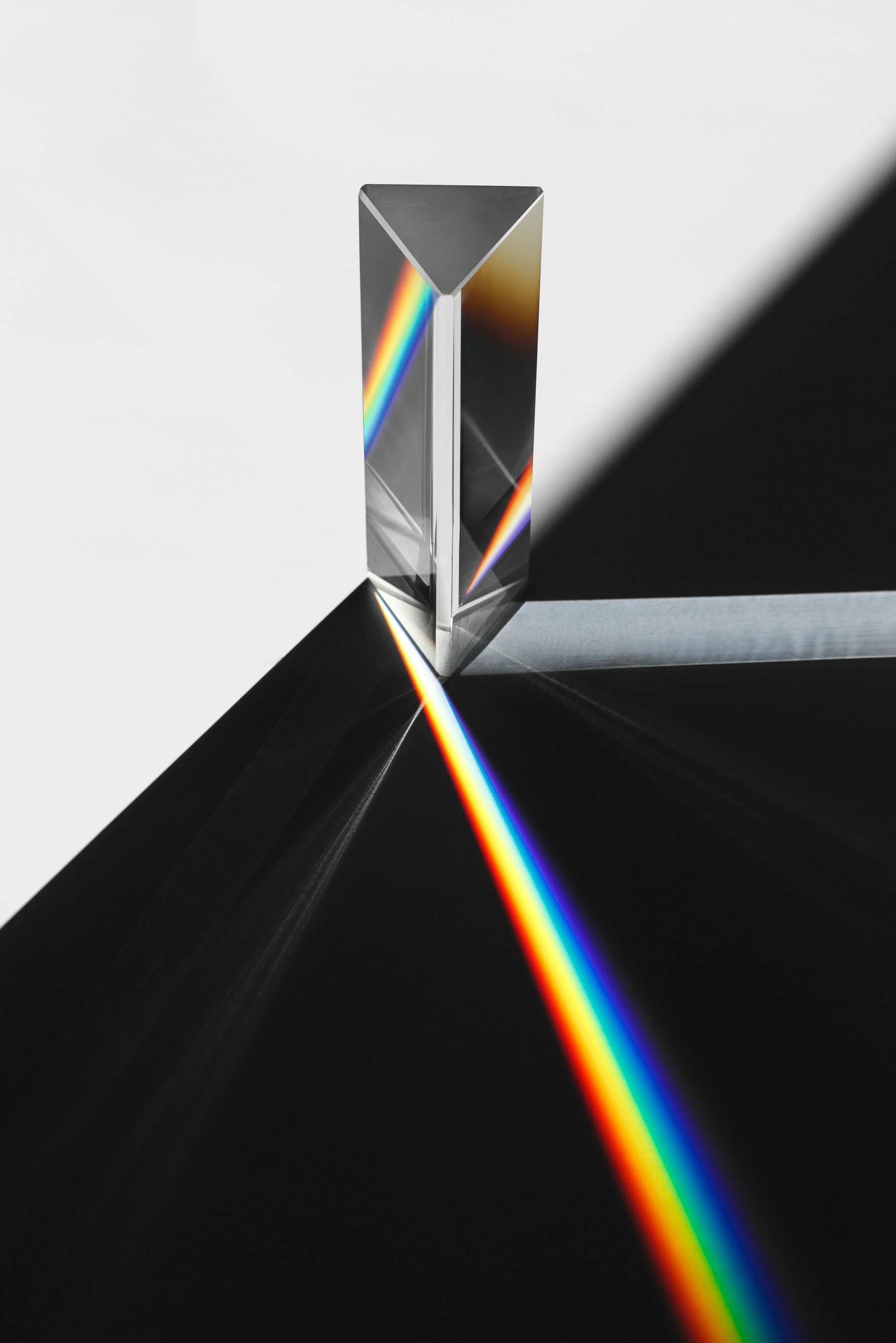 A prism dispersing sunlight splitting into a spectrum on a white background